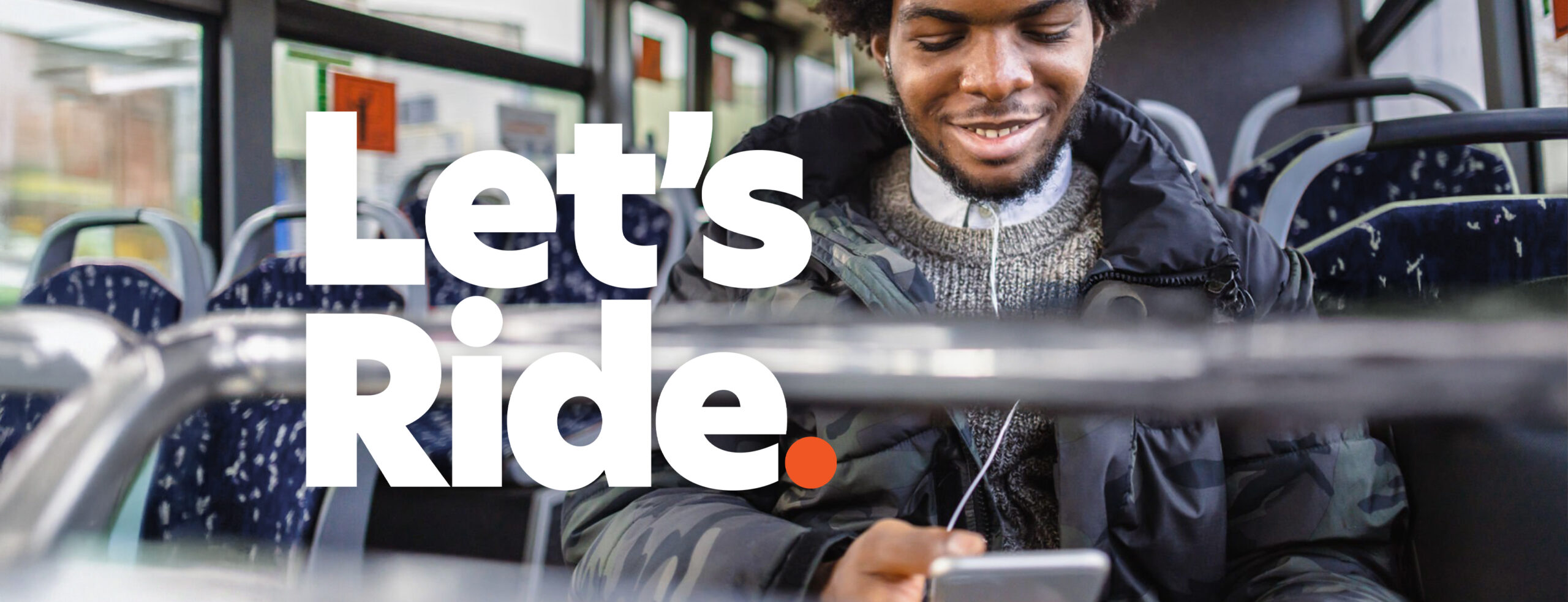 man sitting on bus with headphones holding an iPad. Text says let's ride.